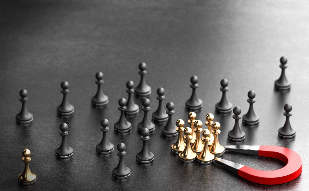 black and gold chess pieces with a magnet drawing gold ones into a group