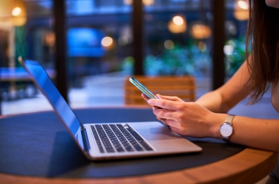 responsive web design concept - woman using a phone and laptop in a cafe